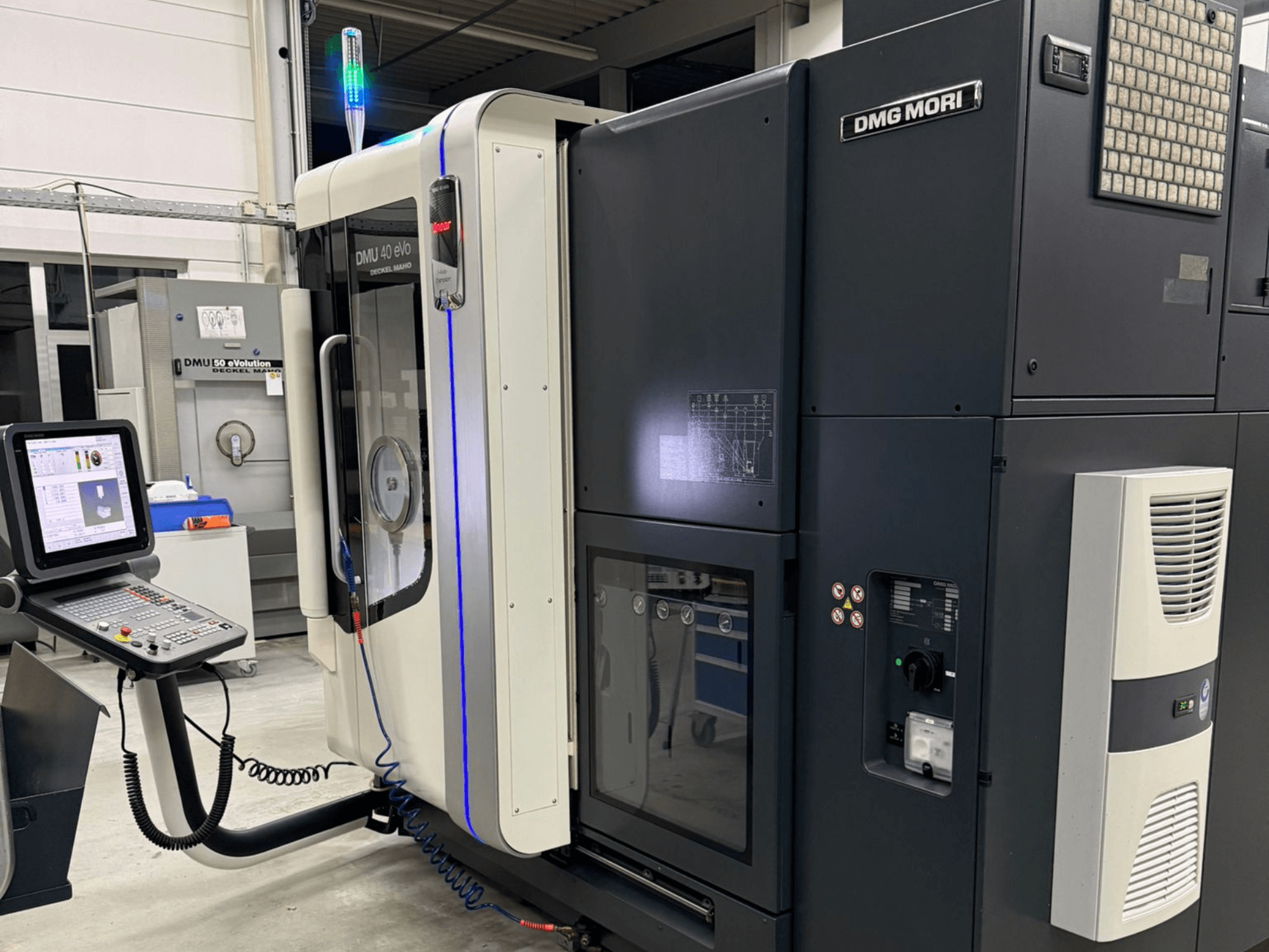 Stroj DMG MORI DMU 40 eVo, pohled zepředu s ovládacími prvky, LED indikátory a elegantním designem zdůrazňujícím průmyslové prvky.