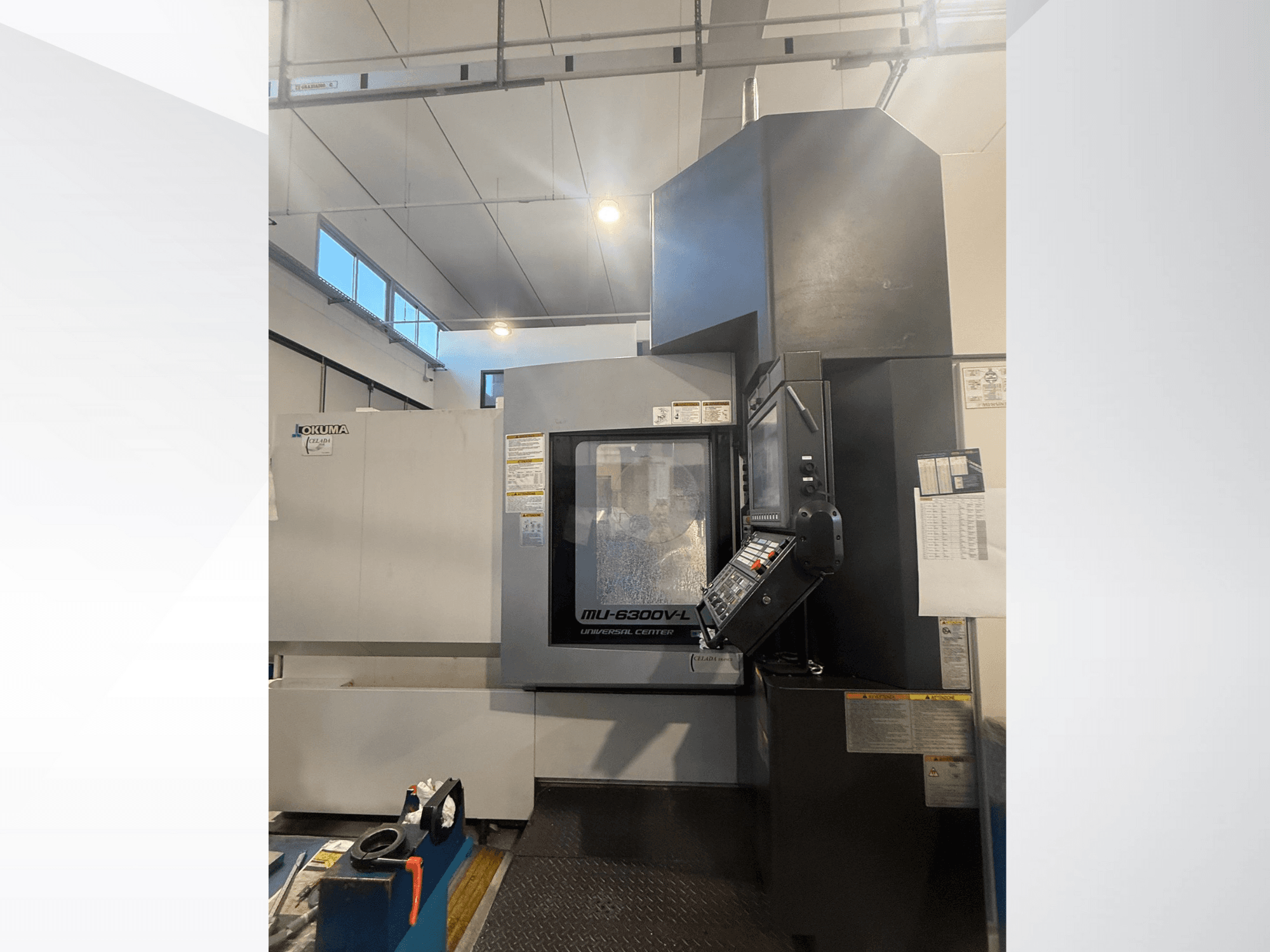 CNC stroj Okuma MU-6300V-L při pohledu zepředu, s ovládacím panelem a bezpečnostními štítky.