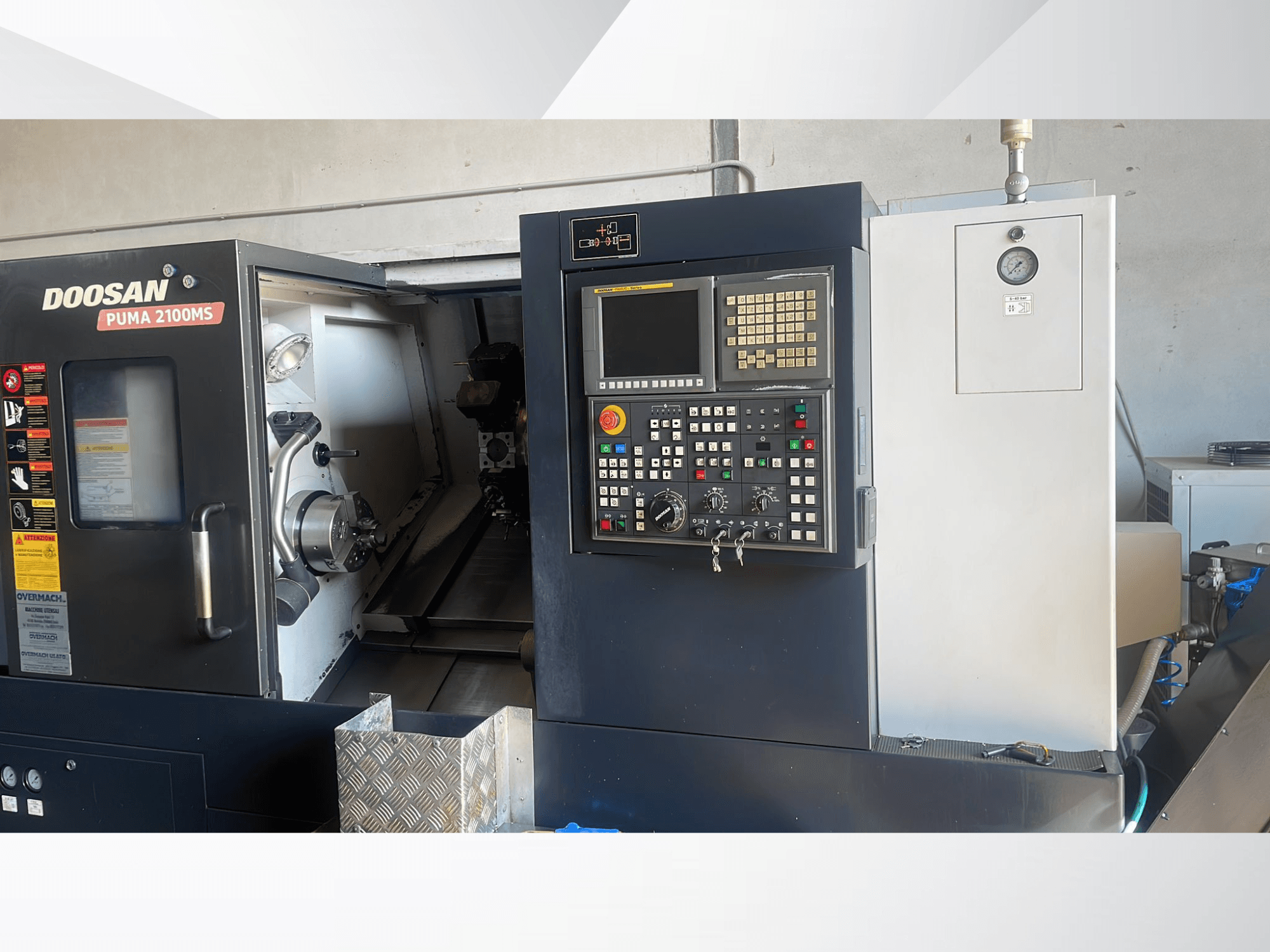 Pohled zepředu na horizontální soustruh DOOSAN PUMA 2100MS s ovládacím panelem, vřetenem a řeznými nástroji uvnitř pracovní komory.
