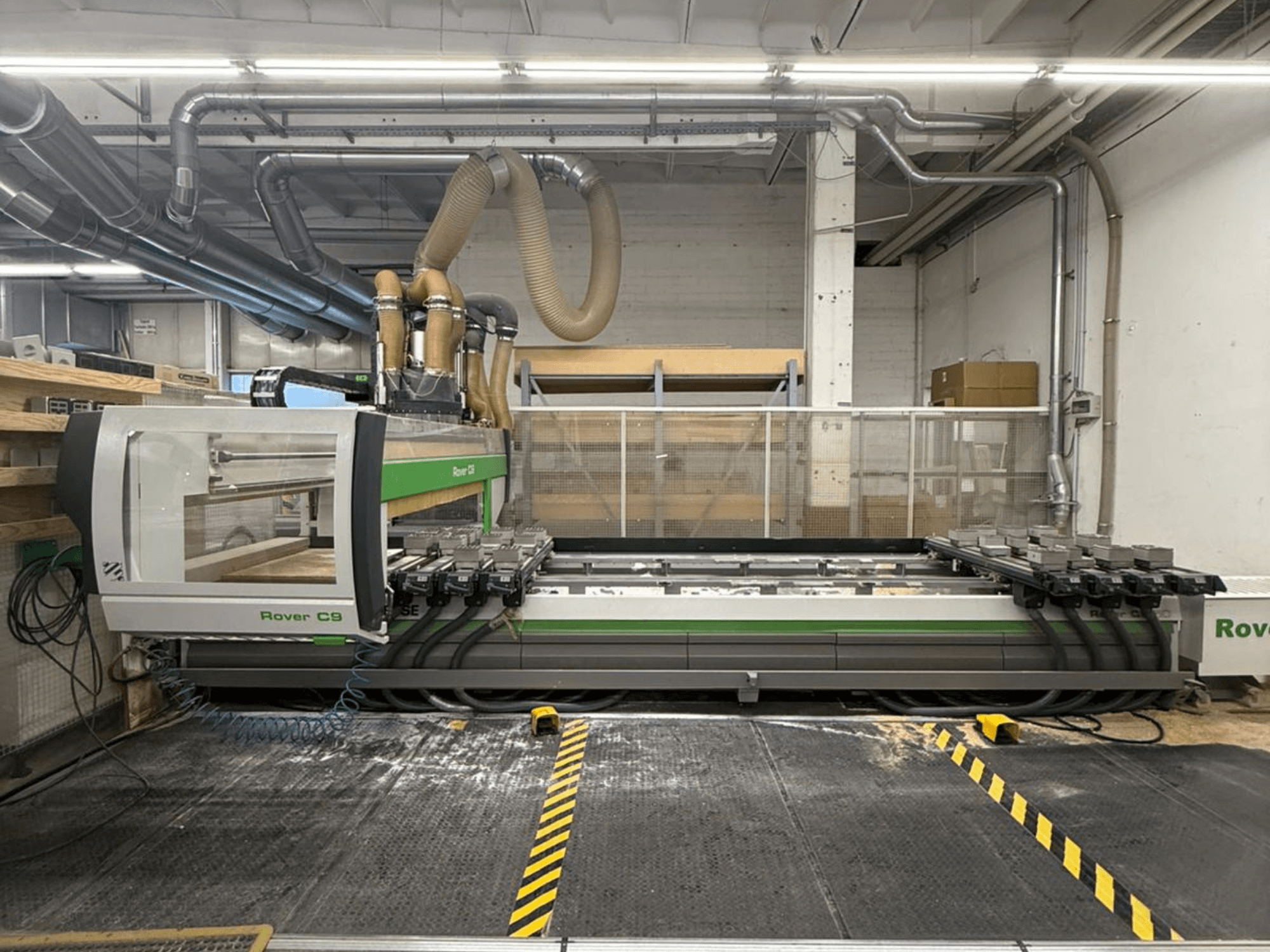 CNC stroj Rover C9 v dílně, pohled zepředu, s více řeznými hlavami a viditelným systémem odsávání prachu.