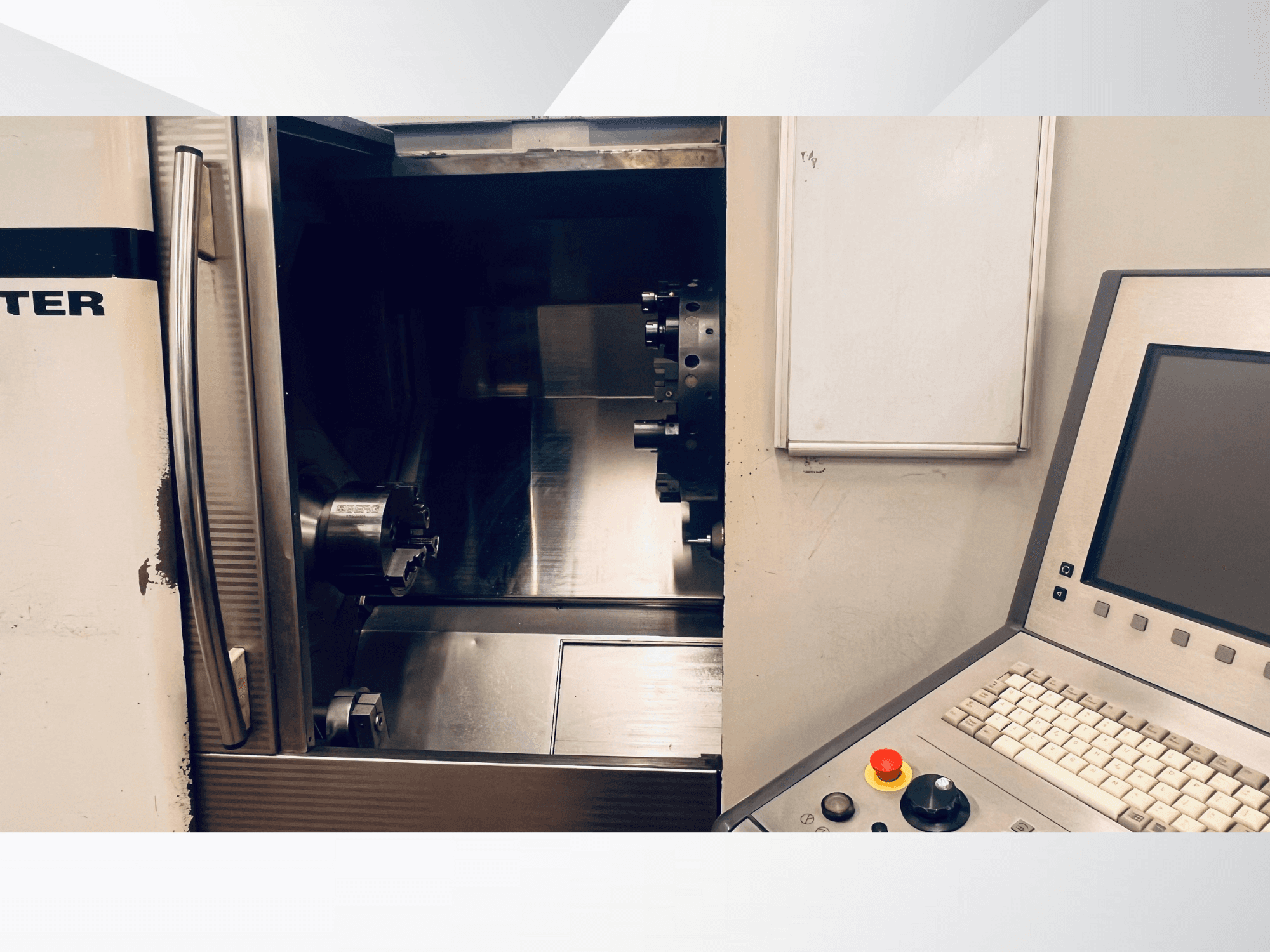 Čelní pohled na CNC stroj zobrazující otevřenou komoru a ovládací panel s klávesnicí a tlačítkem nouzového zastavení.