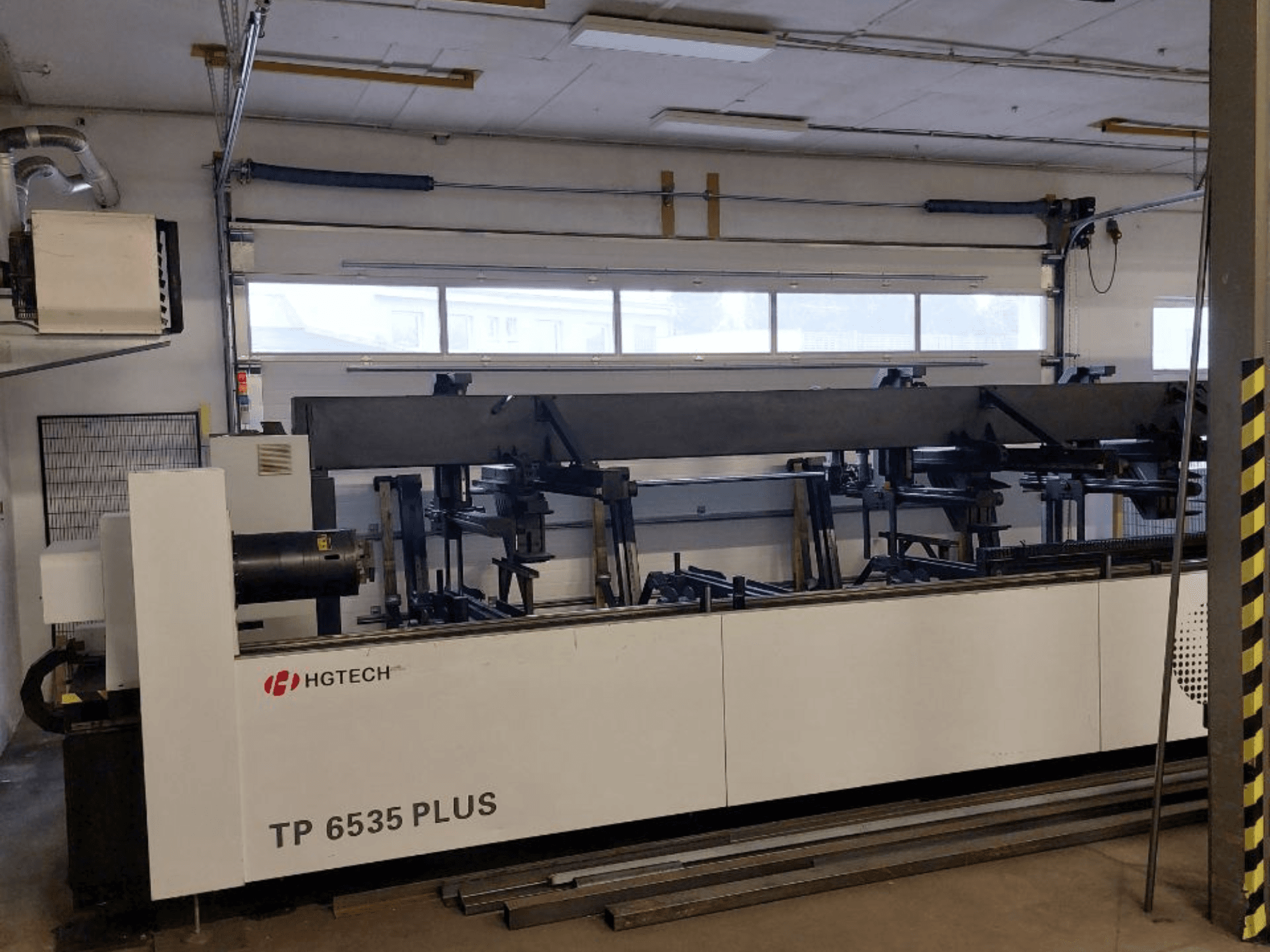 HGTECH TP 6535 PLUS, čelní pohled na velký průmyslový stroj s několika rameny pro přesnou výrobu, umístěný v dílně.