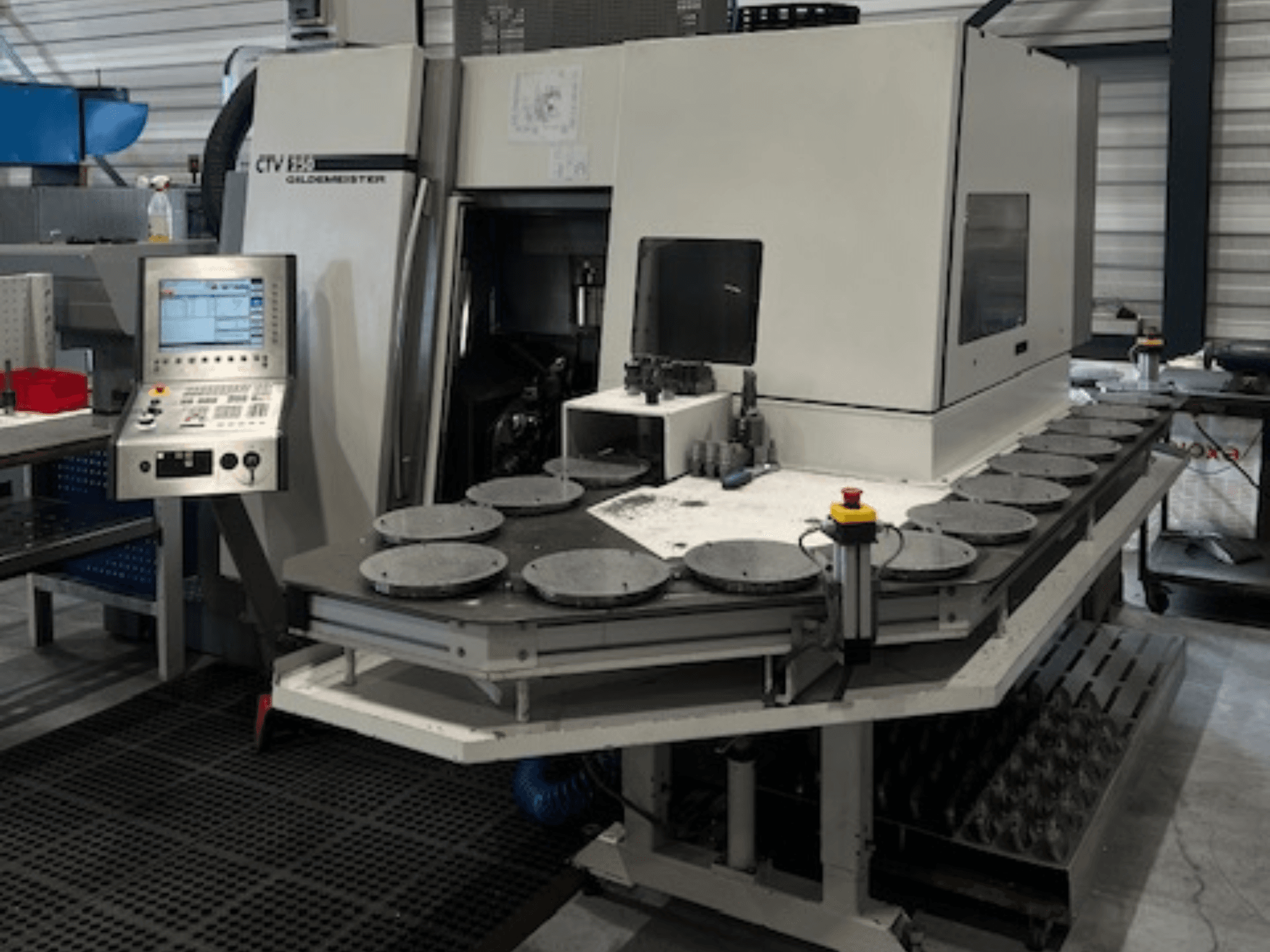 Alt text: CTV E33 Goldmeister v dílně, pohled zepředu, s ovládacím panelem a několika kruhovými pracovními plošinami.