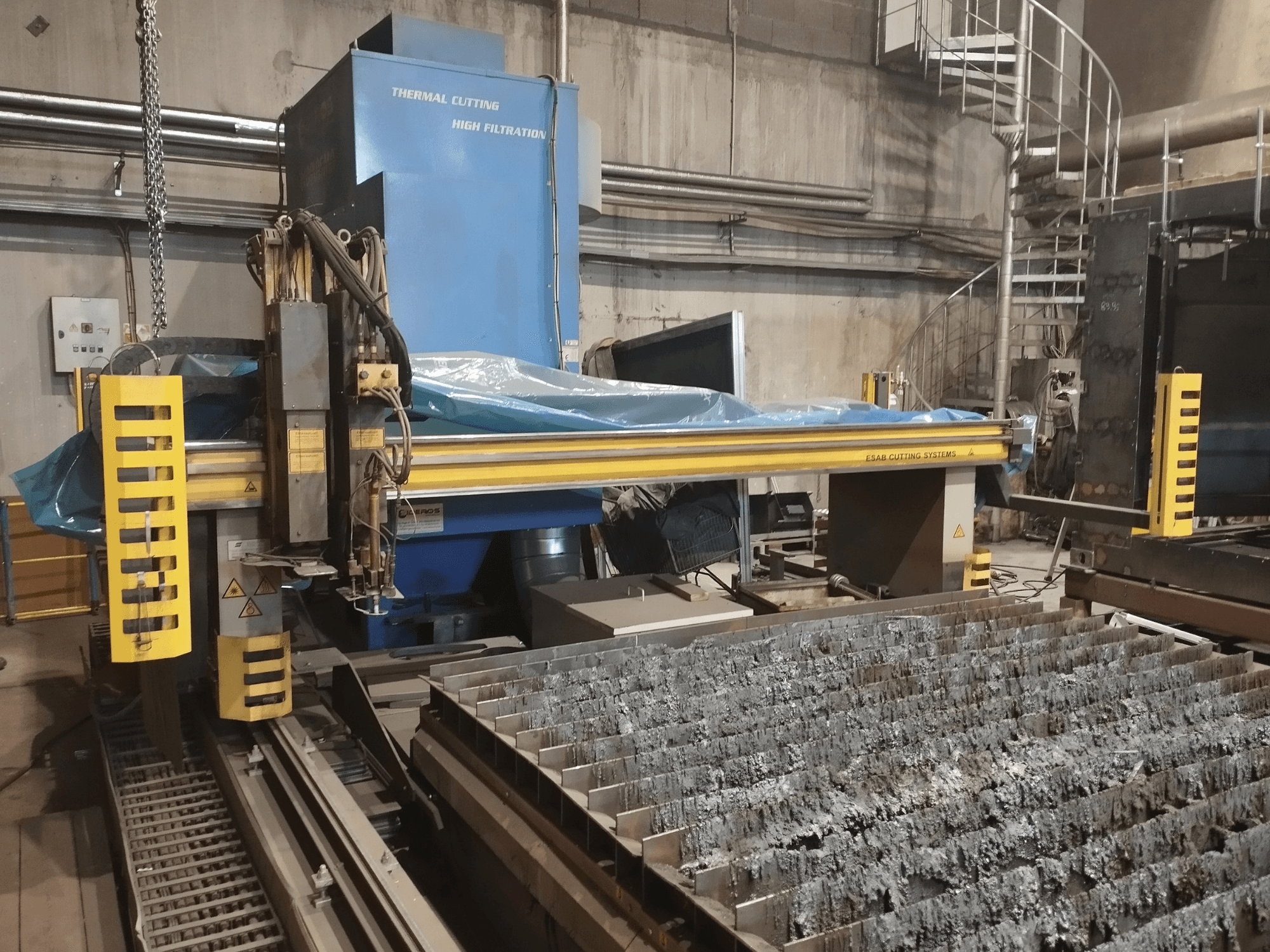 Oxy plazmový řezací stroj ESAB Combirex DX3500, pohled zepředu, se žlutými bezpečnostními prvky a stolem na řezání kovů.