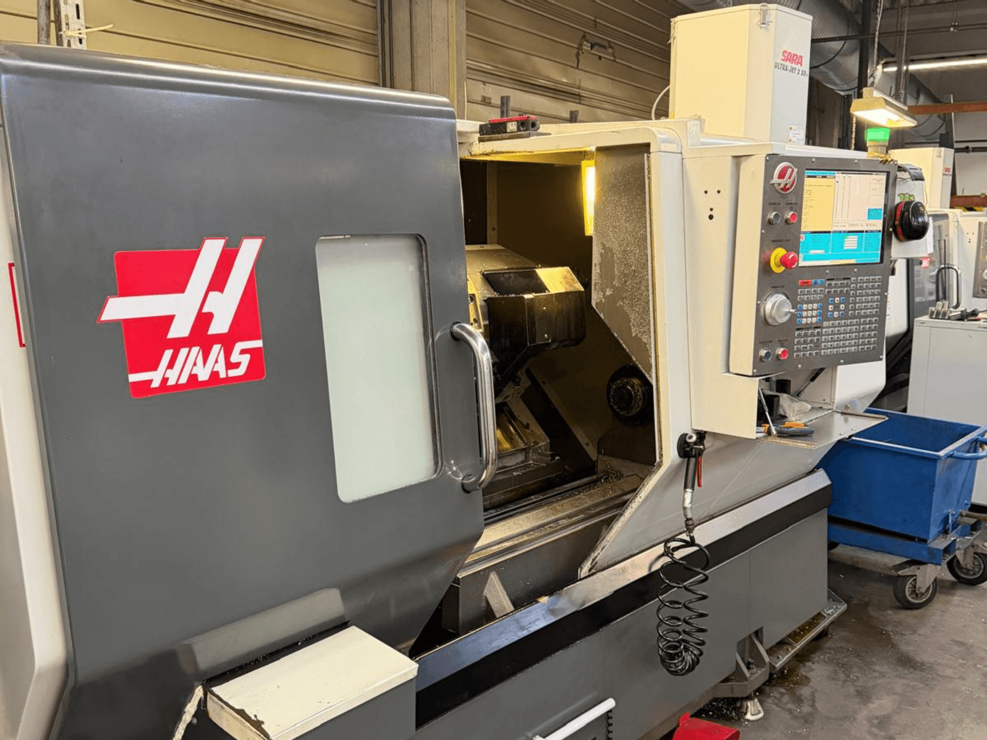 Horizontální soustruh HAAS DS-30SSY, pohled zepředu, s viditelným ovládacím panelem a vnitřními součástmi, v dílenském prostředí.