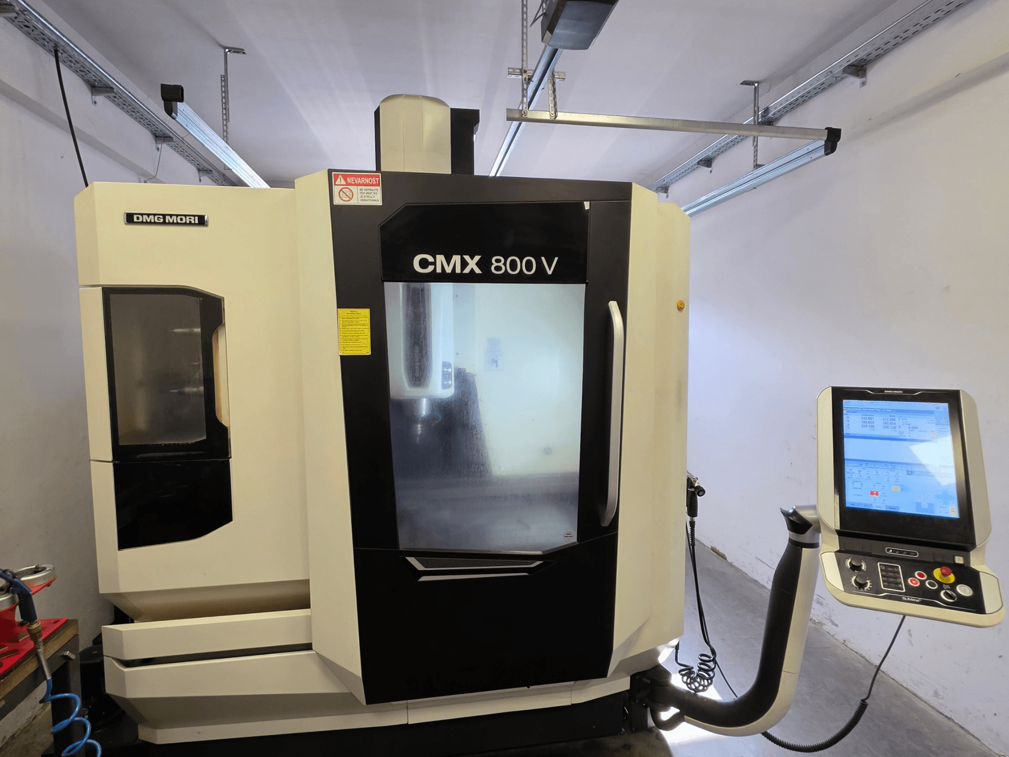 Vertikální obráběcí centrum DMG MORI CMX 800V, pohled zepředu, s dotykovým ovládacím panelem a jasným bezpečnostním značením.