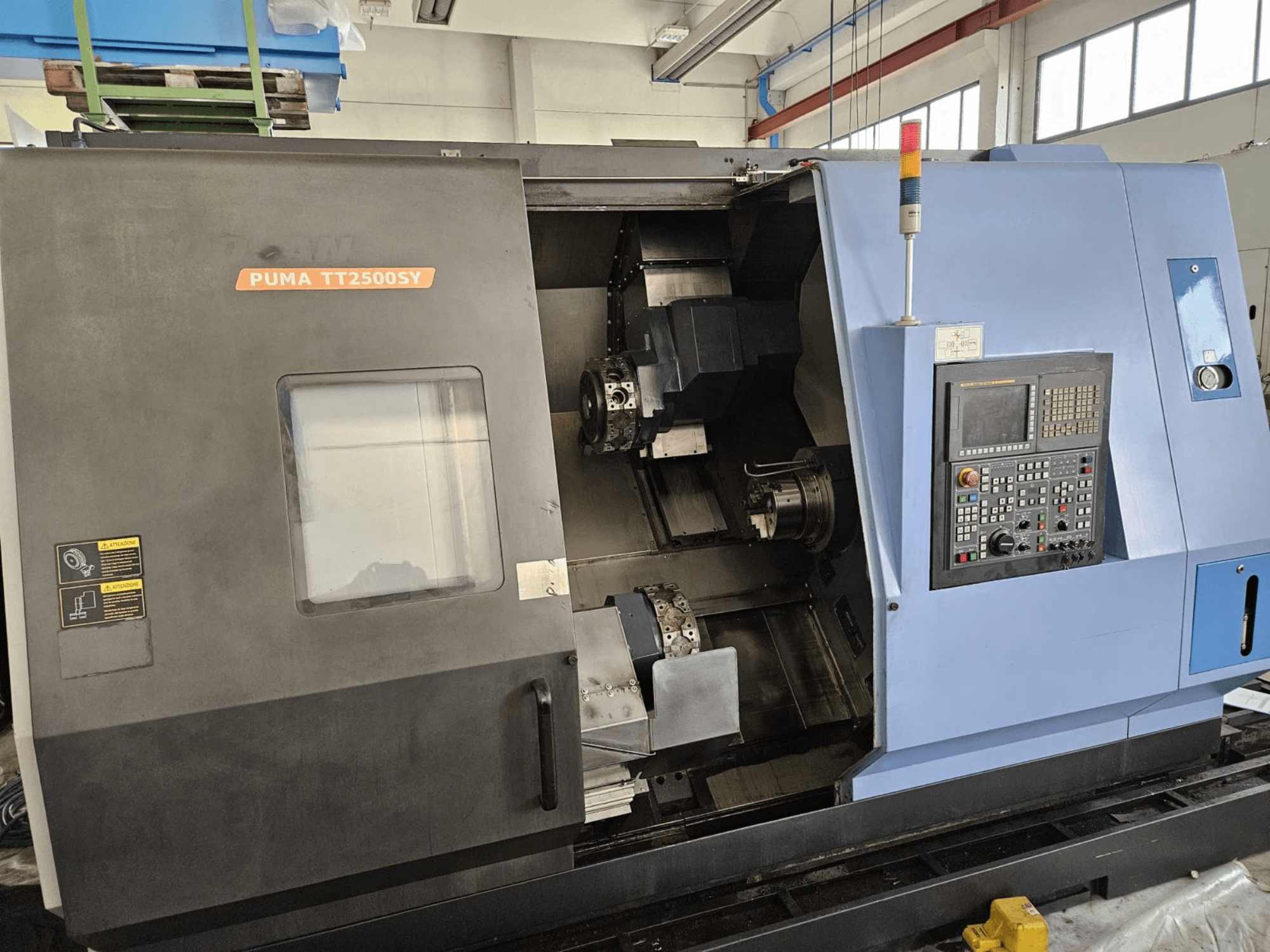 Vícevřetenový soustruh DOOSAN PUMA TT2500SY, pohled zepředu s ovládacím panelem a detaily vnitřního prostoru stroje.