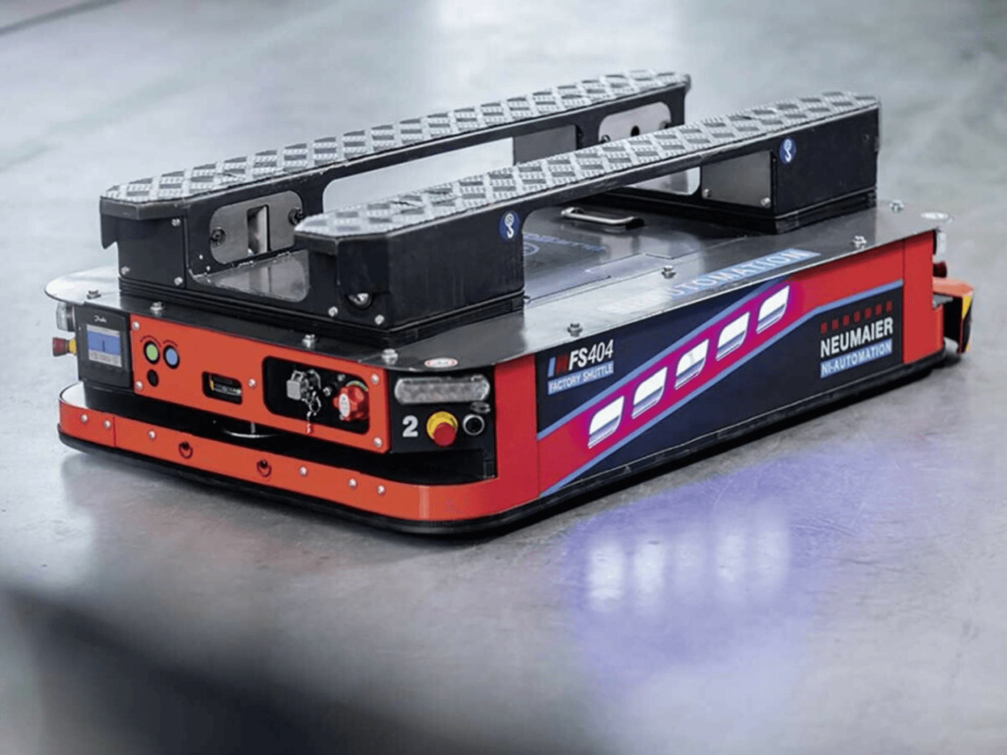 NEUMAIER AGV Factory Shuttle FS404, nízkoprofilový systém pro manipulaci s paletami, boční pohled na kola, ovládací prvky a bezpečnostní prvky.