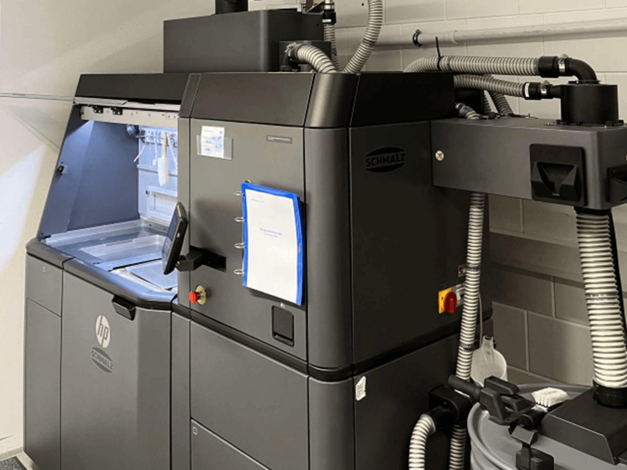 3D tiskárna na plasty HP Jet Fusion 3D 4200, boční pohled, na kterém je vidět ovládací panel a vnitřní součásti.