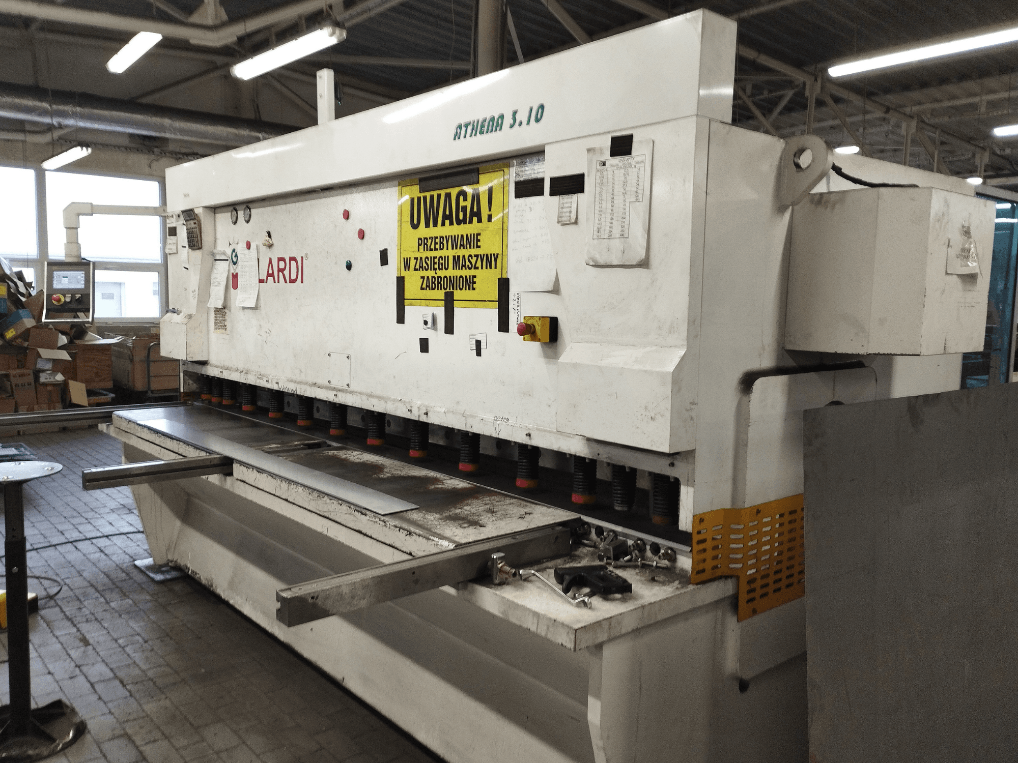 Stroj na stříhání GILARDI ATHENA 3.10 CNC v dílně, pohled zepředu, na kterém jsou vidět ovládací panel a stříhací nože.