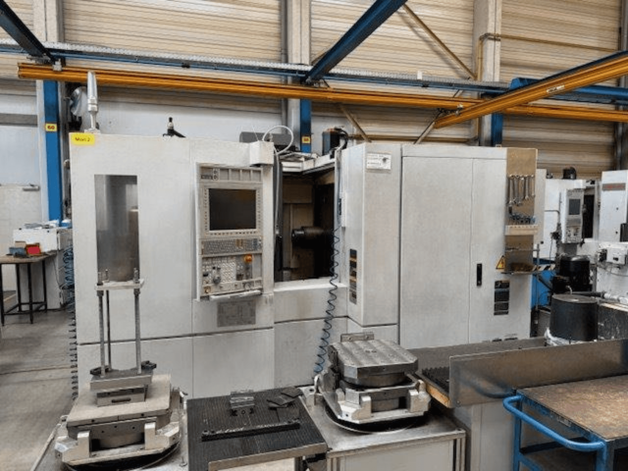 MORI SEIKI NH4000 DCG pohled zepředu na horizontální obráběcí centrum s ovládacím panelem a obrobky na stole.