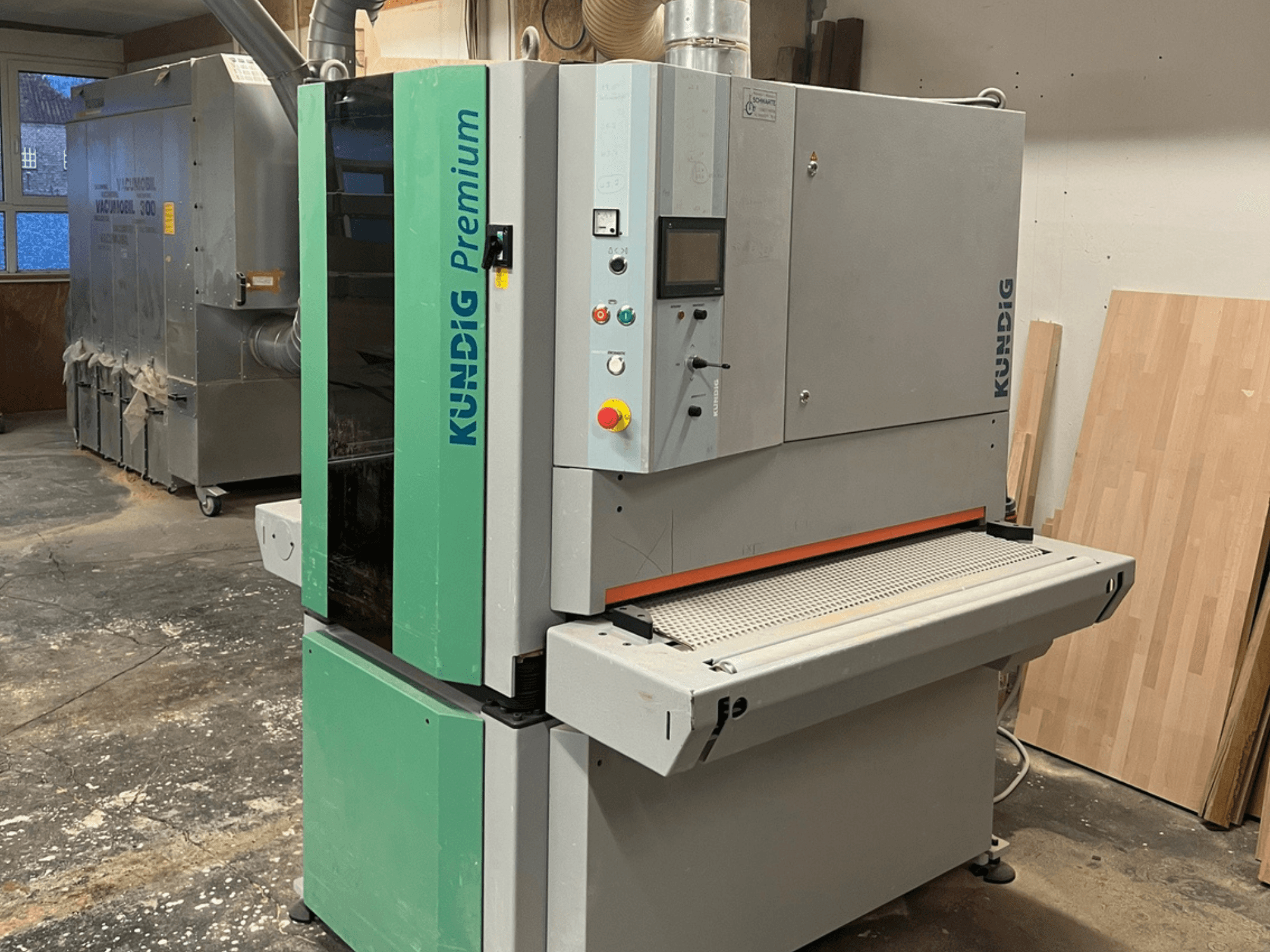 Pásová bruska Kundig Premium-1 1100K v šedé a zelené barvě, zobrazená z bočního pohledu s viditelným ovládacím panelem a brusným pásem.