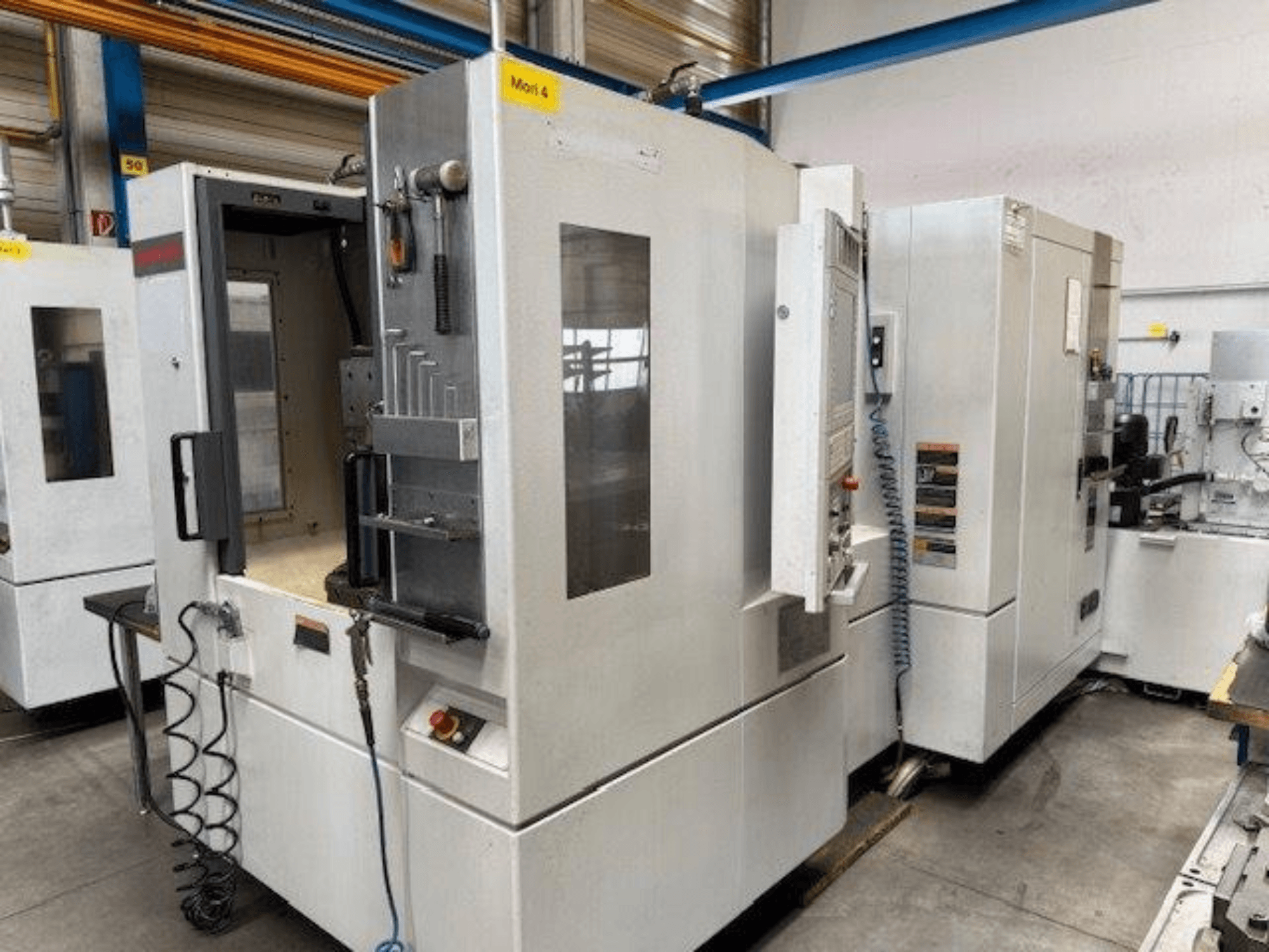 Horizontální obráběcí centrum MORI SEIKI NH4000 DCG zobrazené zepředu, s otevřenými dveřmi a detaily ovládacího panelu.
