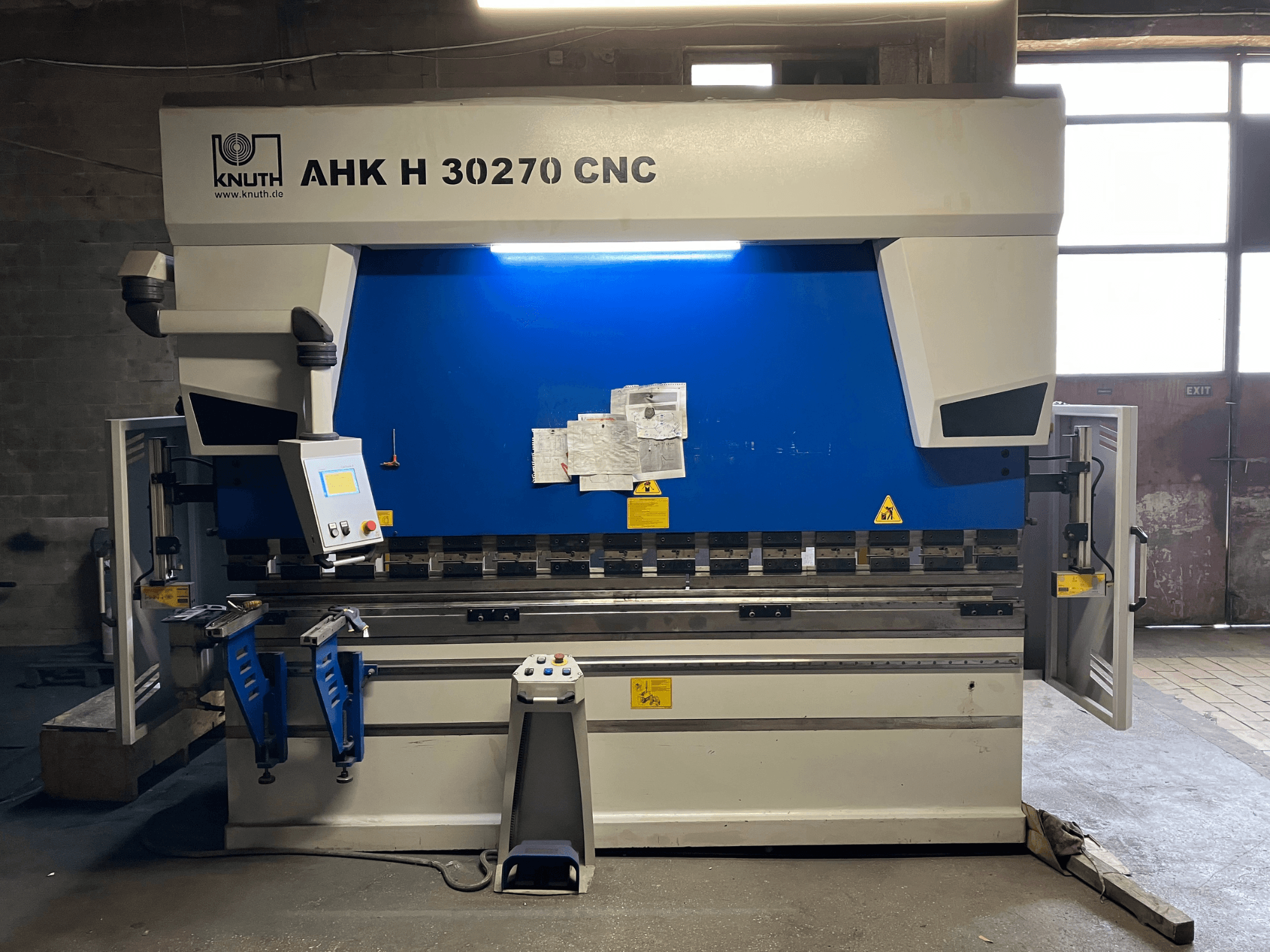 Ohýbačka KNUTH AHK H 30270 s CNC řízením v dílně, pohled zepředu, s viditelným ovládacím panelem a modro-bílým provedením, s otevřenými bočními dvířky.
