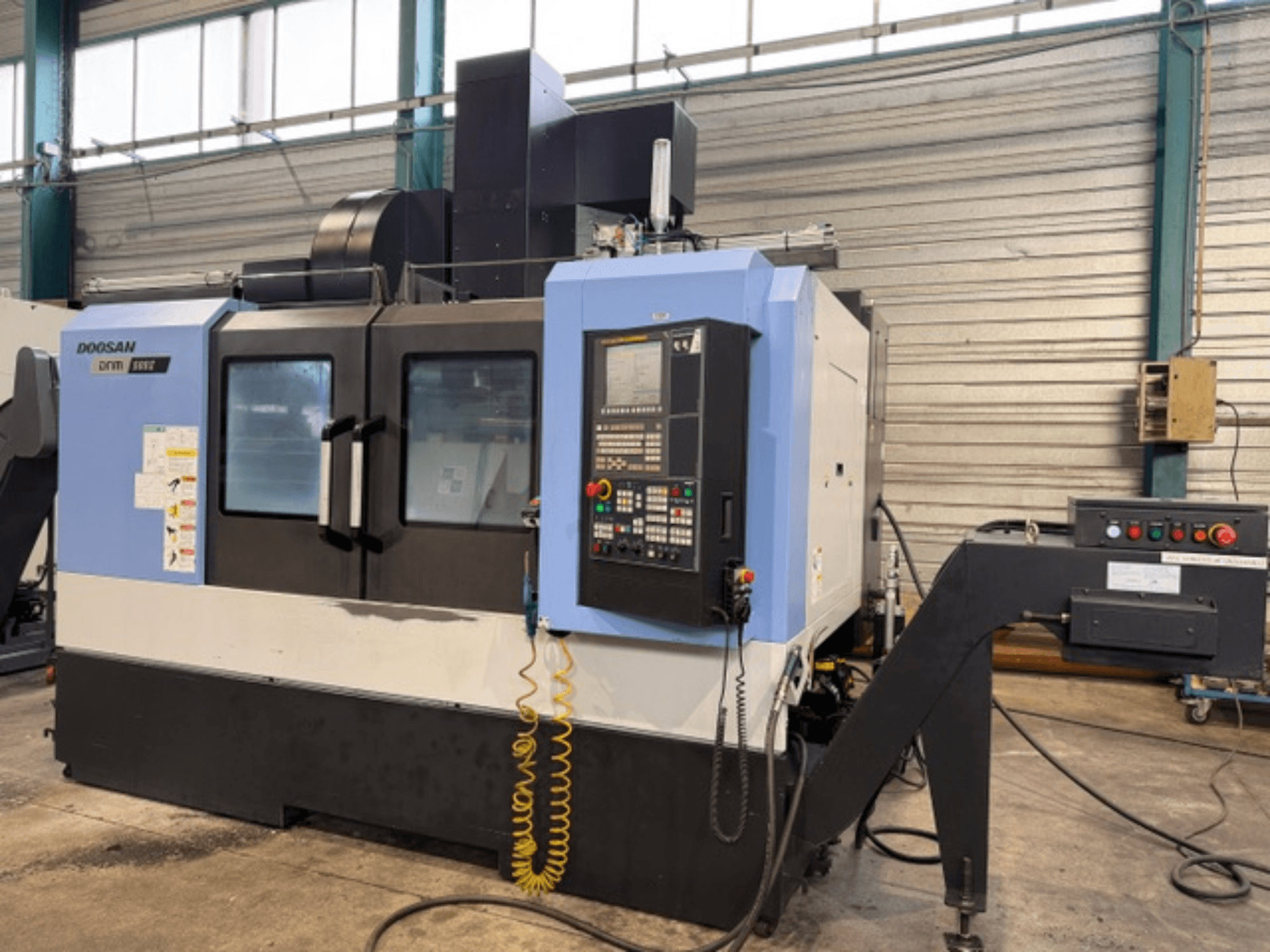 CNC frézka Doosan DNM 500II z čelního pohledu, s ovládacím panelem a držákem nástrojů, v továrním prostředí.