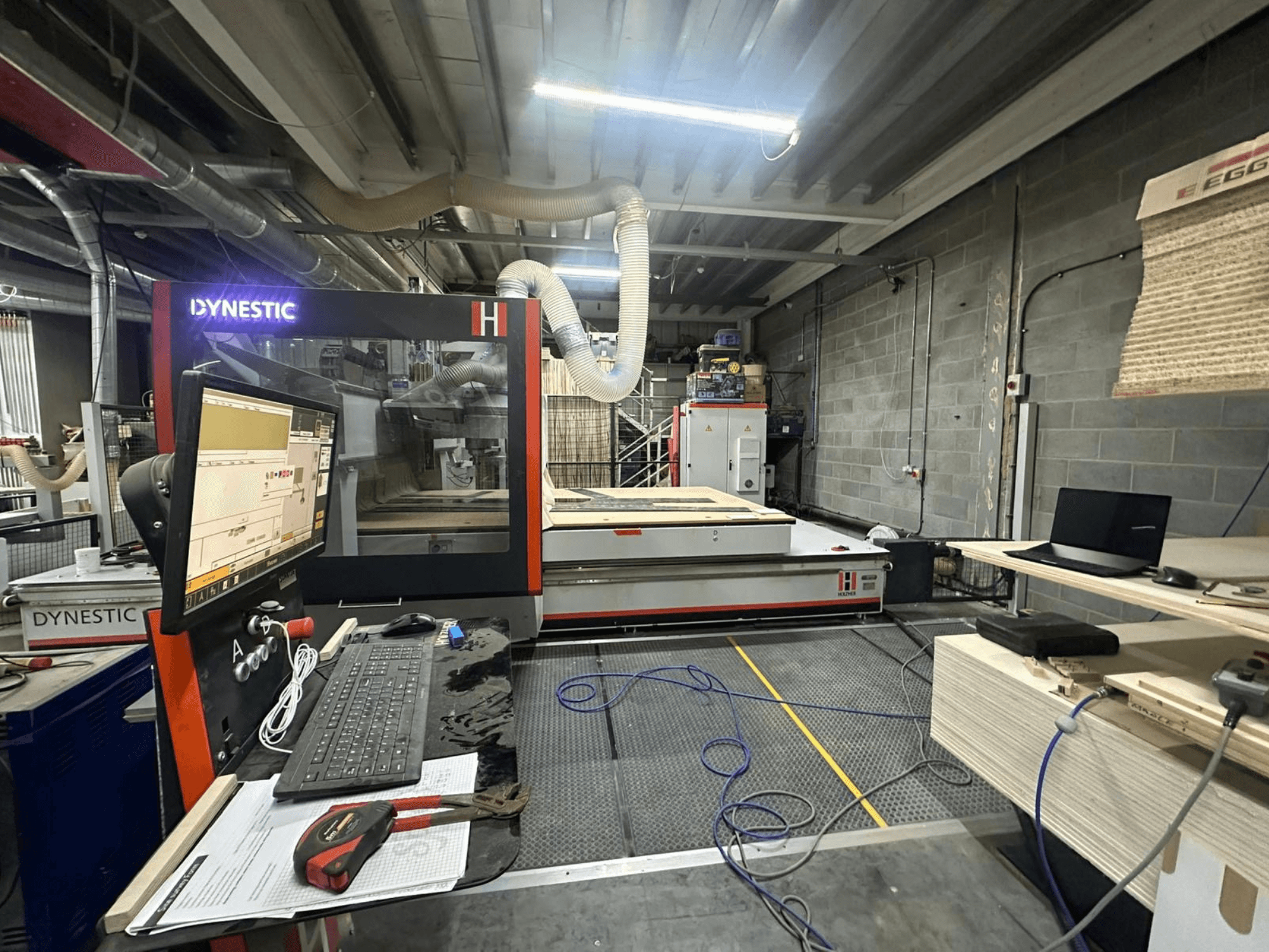 Frézka na dřevo HOLZHER Dynestic 7535 v dílně, ovládací panel, monitor a materiály na pracovním stole, pohled zepředu.