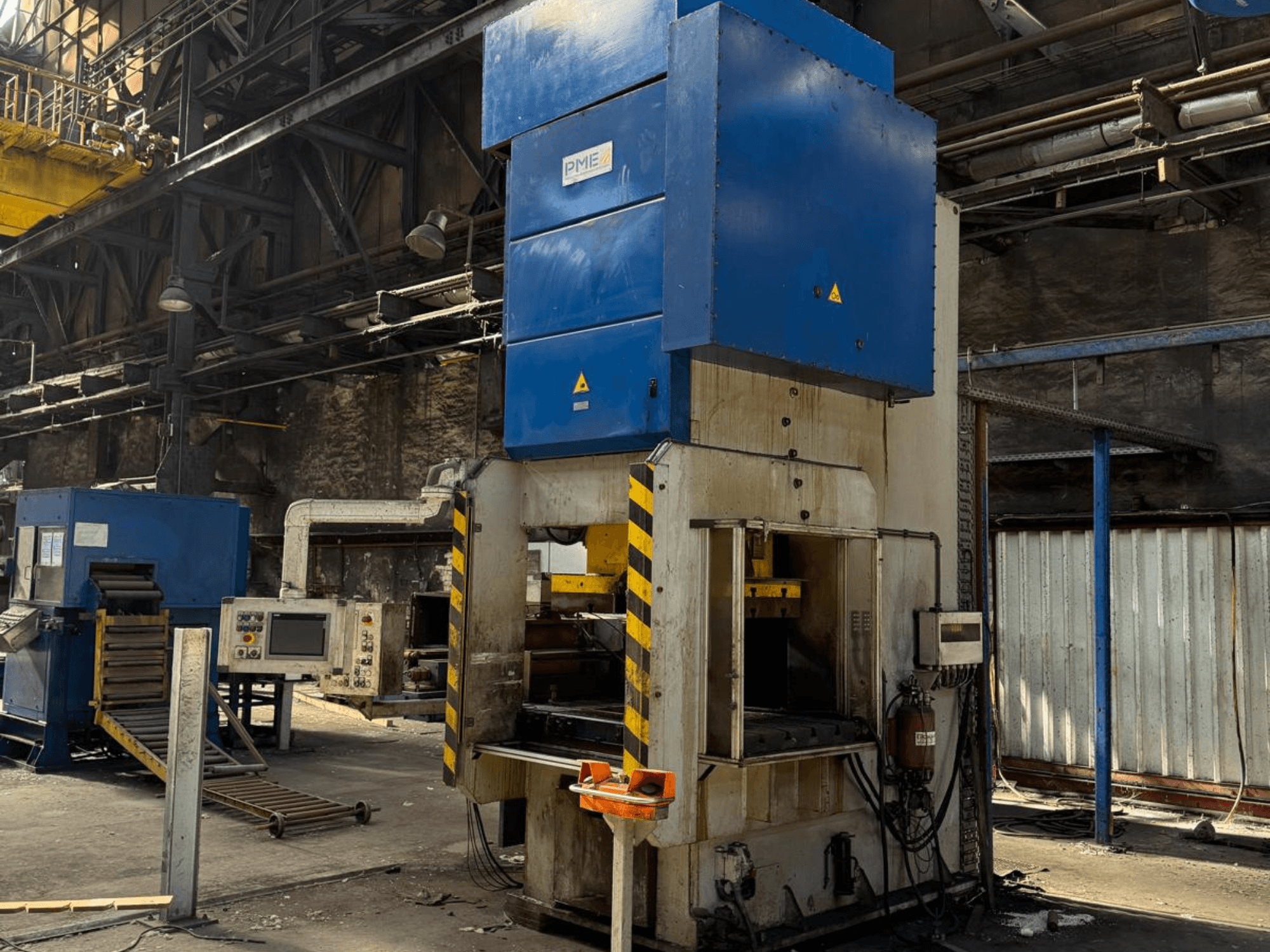 Mechanický lis PME PE 400-1700 C, pohled zepředu, znázorňující modrou horní část a žlutě pruhovanou základnu v továrním prostředí.