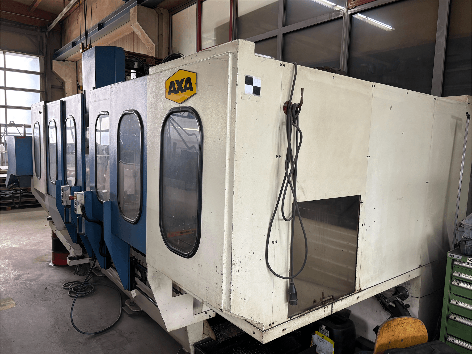 Vertikální obráběcí centrum AXA VSC-1-M/C, pohled zepředu, s velkou bílou skříní a modrým ovládacím panelem.