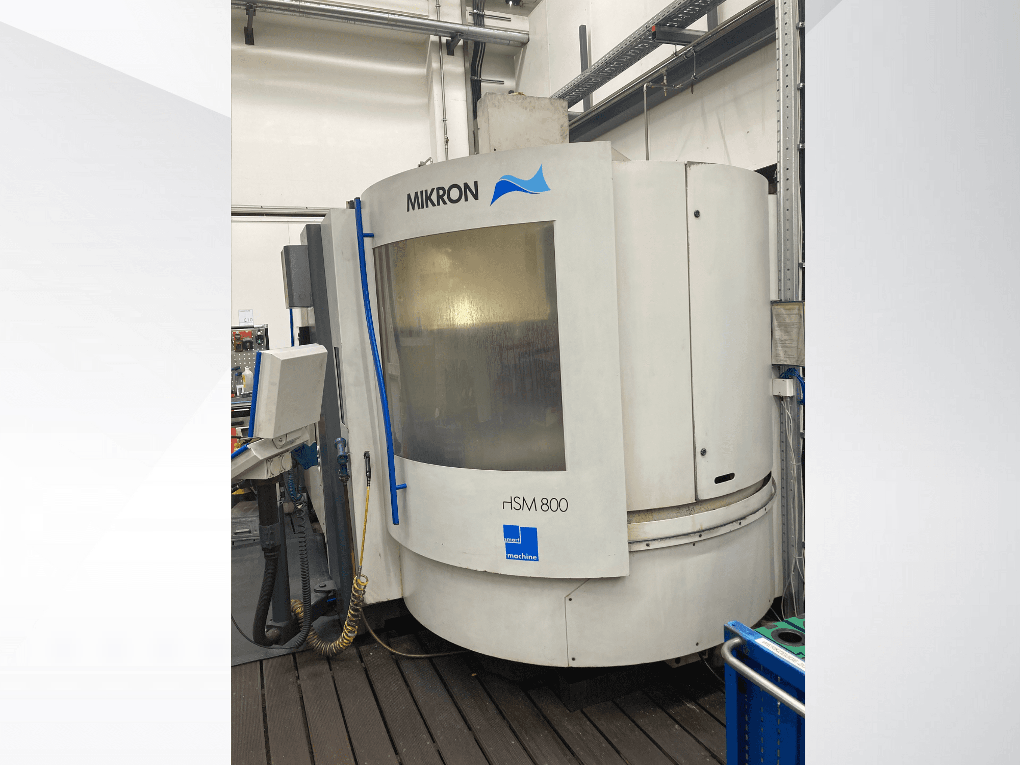 CNC stroj Mikron rISM 800, pohled zepředu s ovládacím panelem, válcovým designem a modrými akcenty, zasazený do dílenského prostředí.