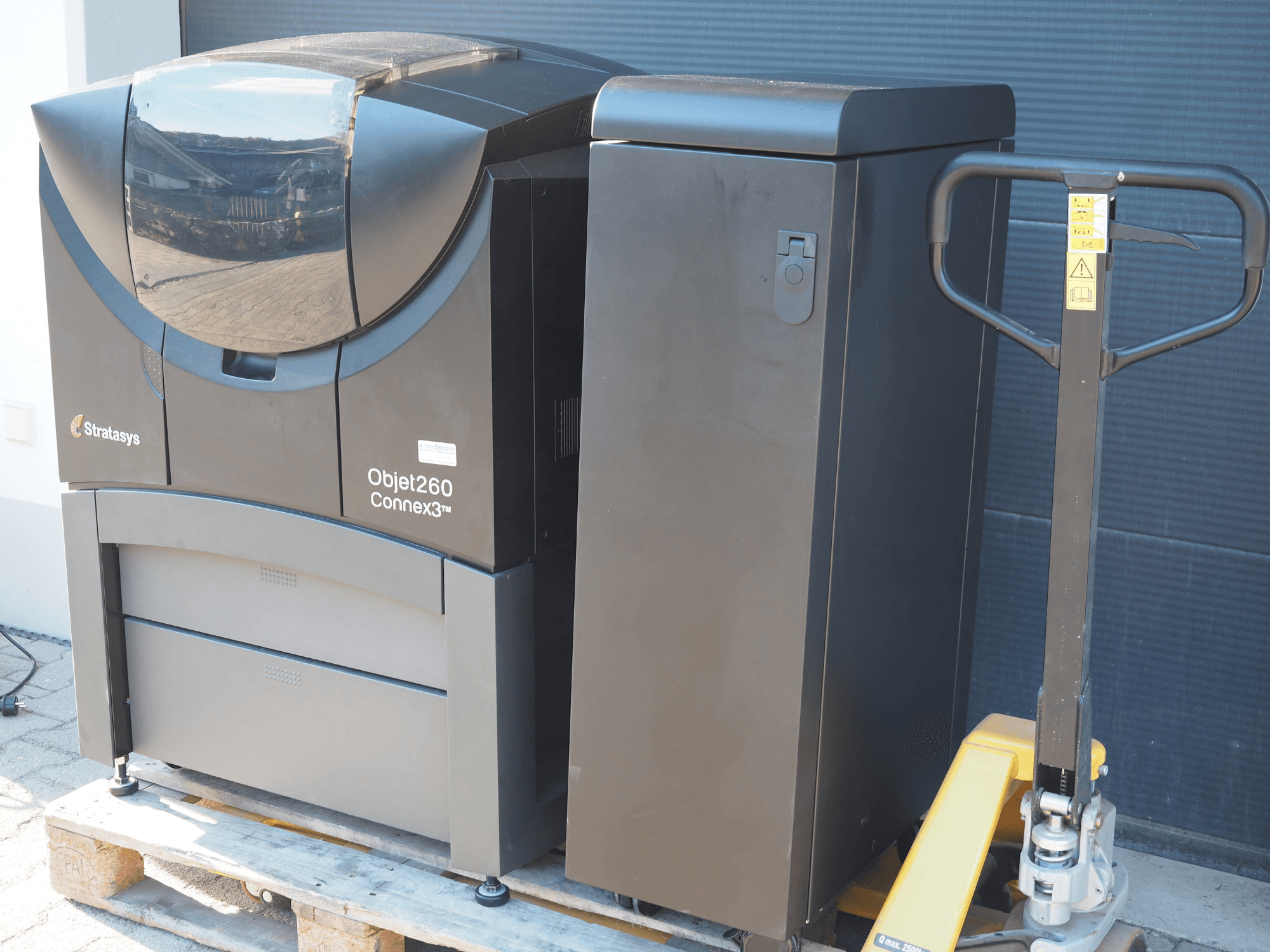 Plastová 3D tiskárna Stratasys Objet260 Connex3, boční pohled, s kompaktním designem s ovládacím panelem a připojeným zásobníkem materiálu.