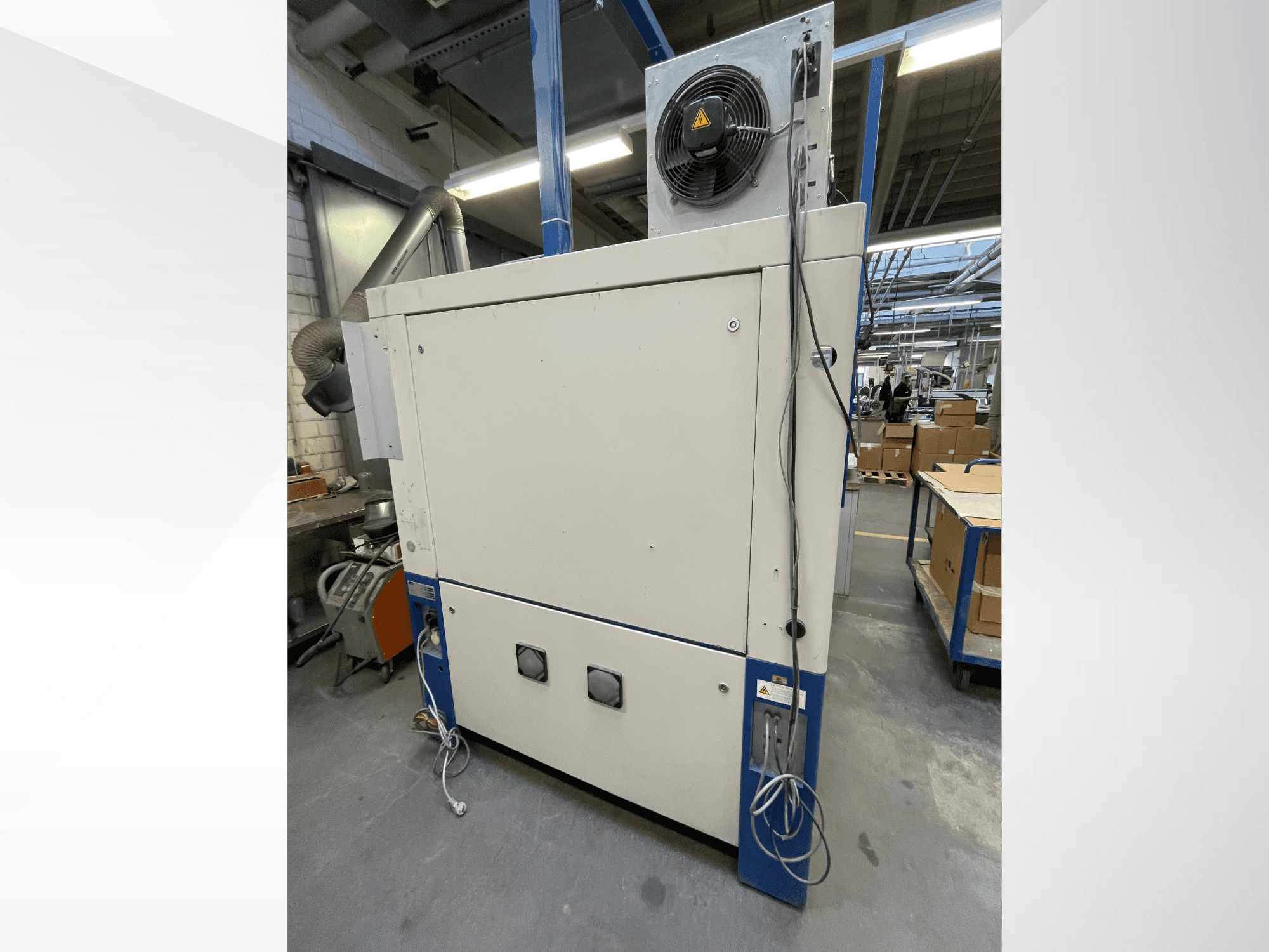 Průmyslový sušicí stroj s ventilátorem, boční pohled; vybaven ventilací a několika elektrickými přípojkami. Značka/model není viditelný.