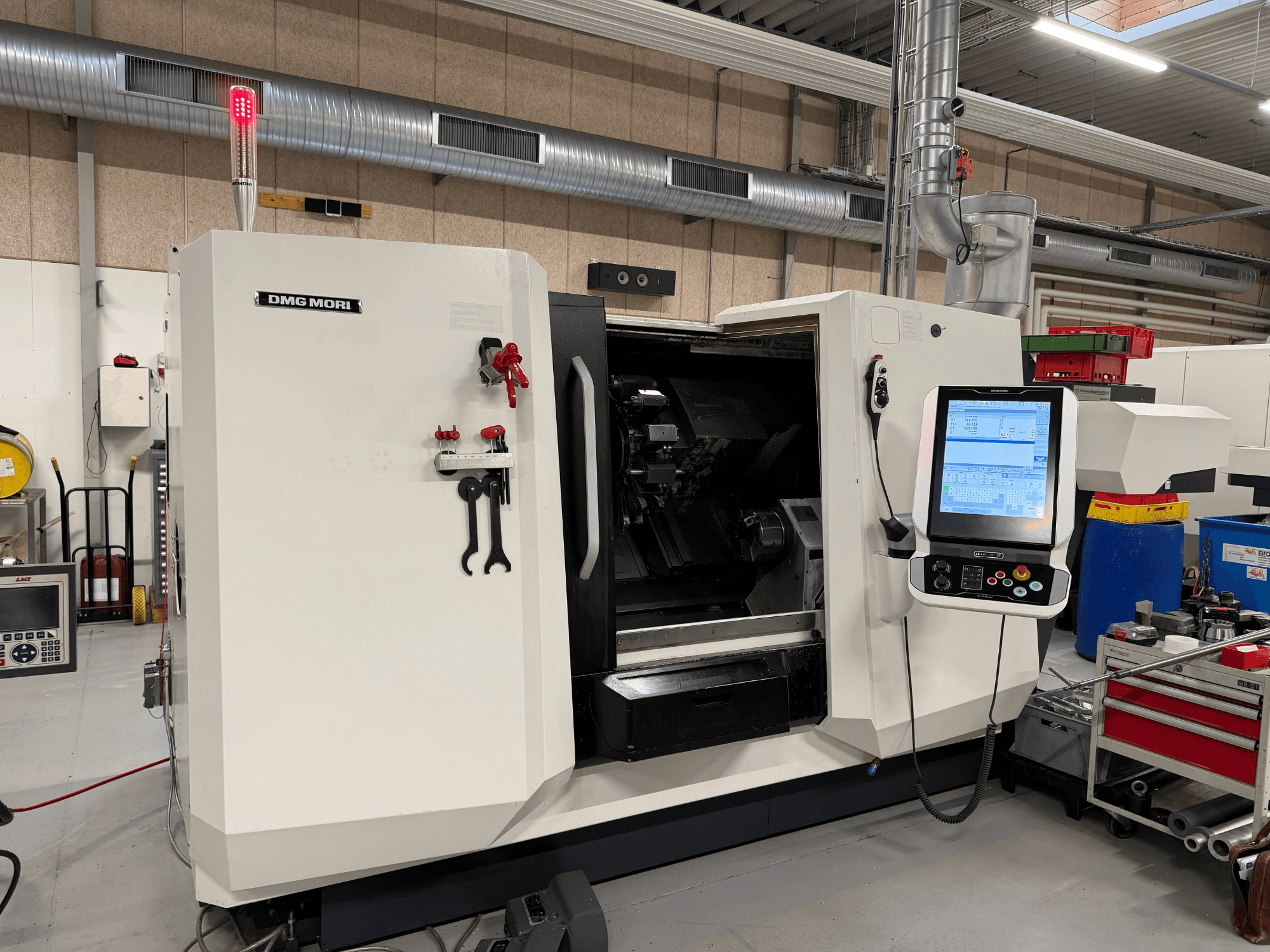 Horizontální soustruh DMG MORI CLX 450 V6, pohled zepředu, na kterém je vidět ovládací panel, nouzové zastavení a bezpečnostní světlo.