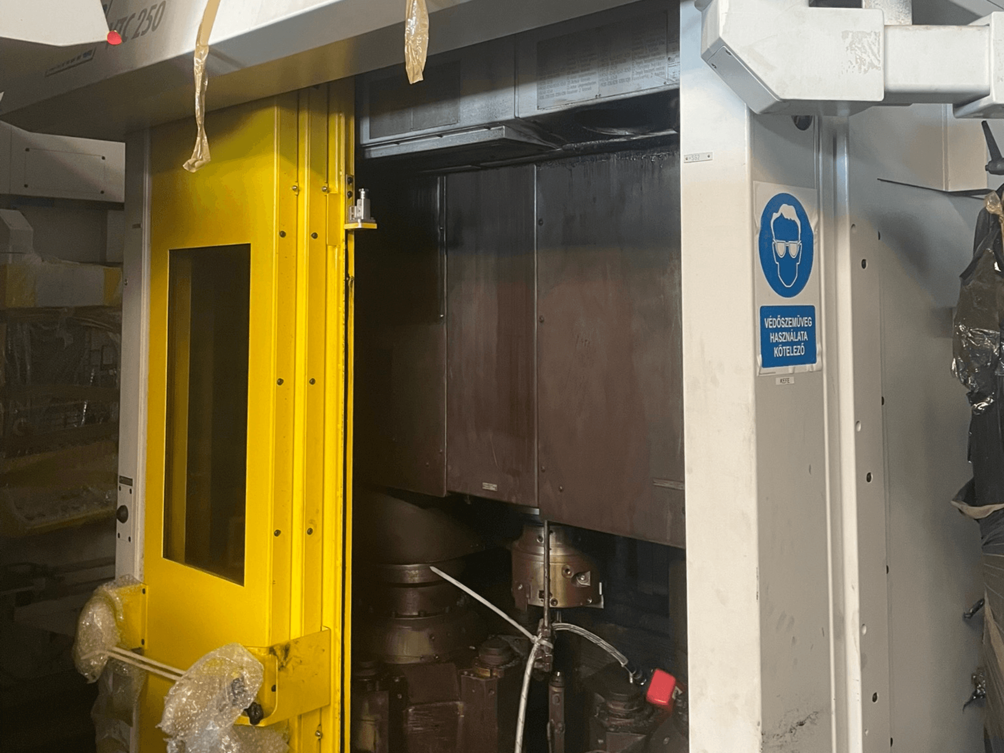 Žluté vstupní dveře stroje s bezpečnostní značkou, pohled zepředu na průmyslový stroj model Z250, zobrazující vnitřní součásti.