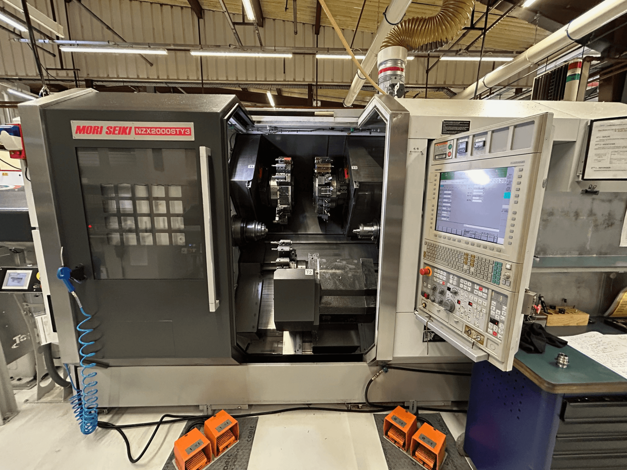 Vícevřetenový soustruh MORI SEIKI NZ2000 ST3Y3, pohled zepředu s ovládacím panelem a obráběcím prostorem.