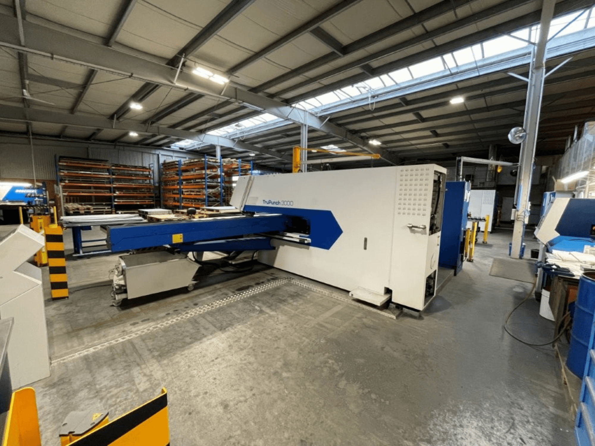CNC děrovací lis TRUMPF TruPunch 3000 v továrním prostředí – pohled zepředu ukazuje jeho modro-bílé provedení a provozní součásti.