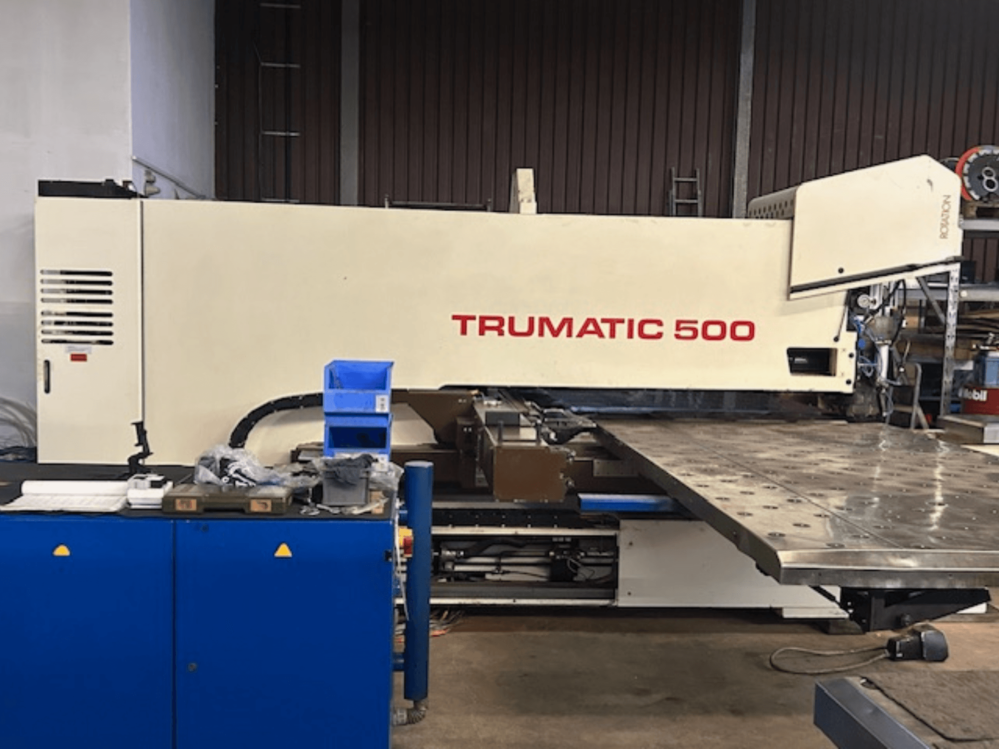 Děrovací stroj TRUMPF TRUMATIC 500 CNC, pohled zepředu, s ovládacím panelem a velkým pracovním stolem s děrovaným povrchem.
