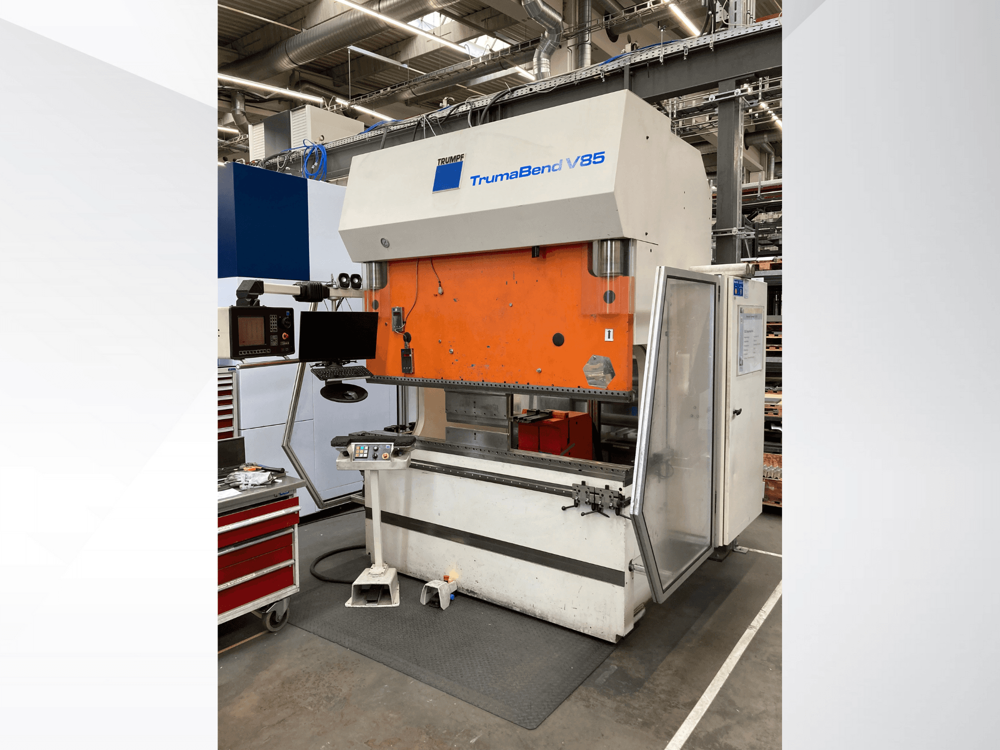 Ohýbačka TruMatic V85 v továrně, s oranžovým čelním panelem, ovládacím displejem a otevřenými bočními dveřmi, pohled z boku.