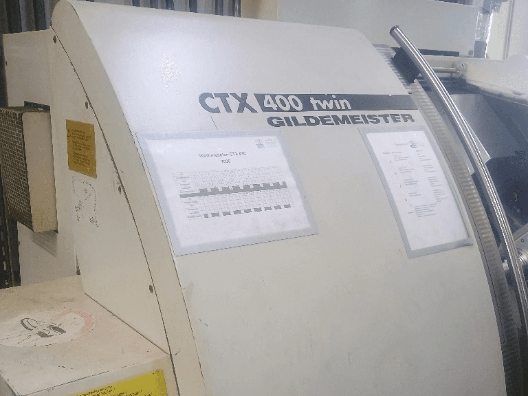Dvouhřídelový horizontální soustruh Gildemeister CTX 400, pohled zepředu, s viditelnými ovládacími panely a technickou dokumentací.