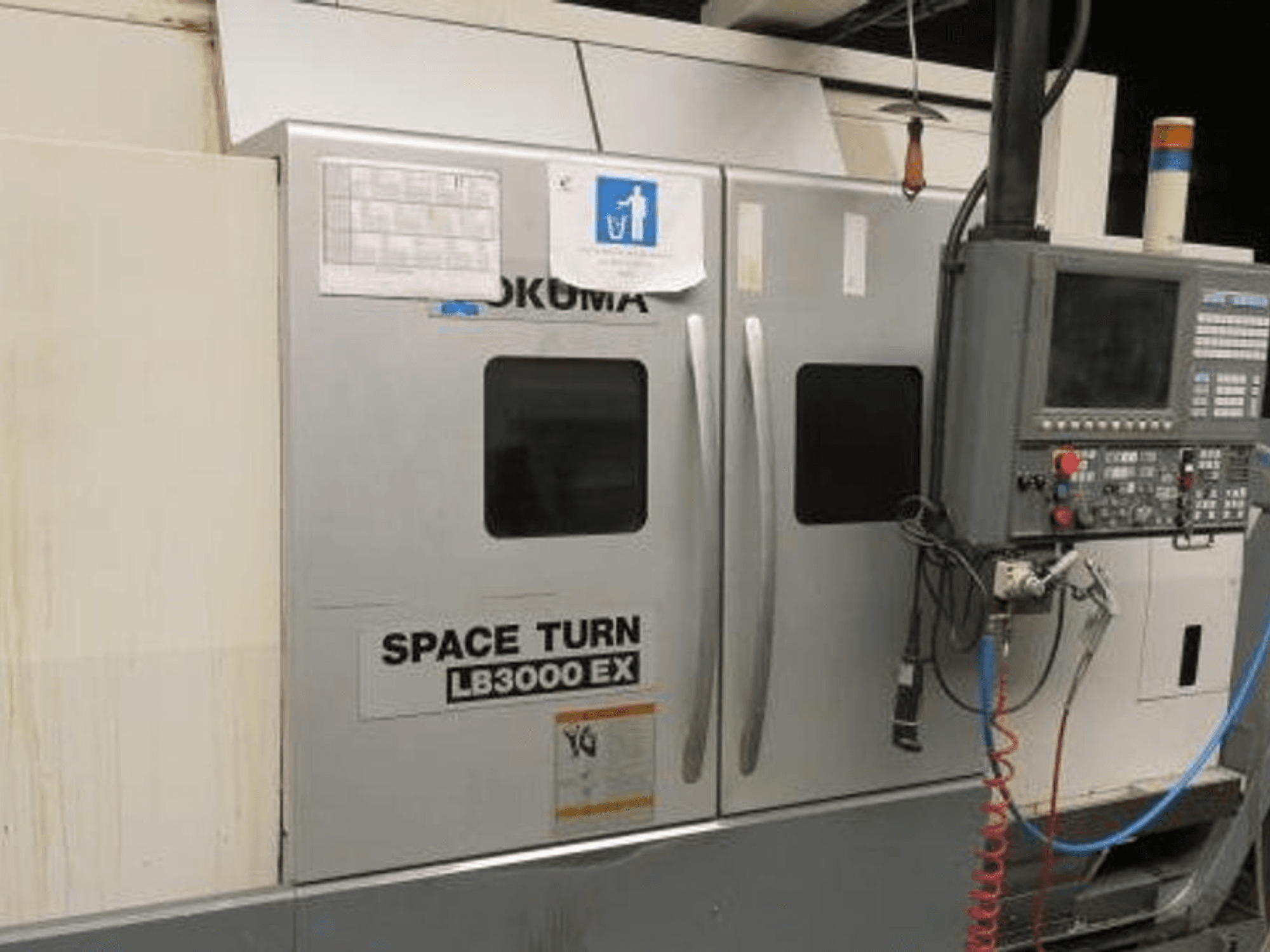 Soustruh Okuma Space Turn LB3000 EX CNC, boční pohled, s ovládacím panelem, dvěma dvířky a viditelnou kabeláží.