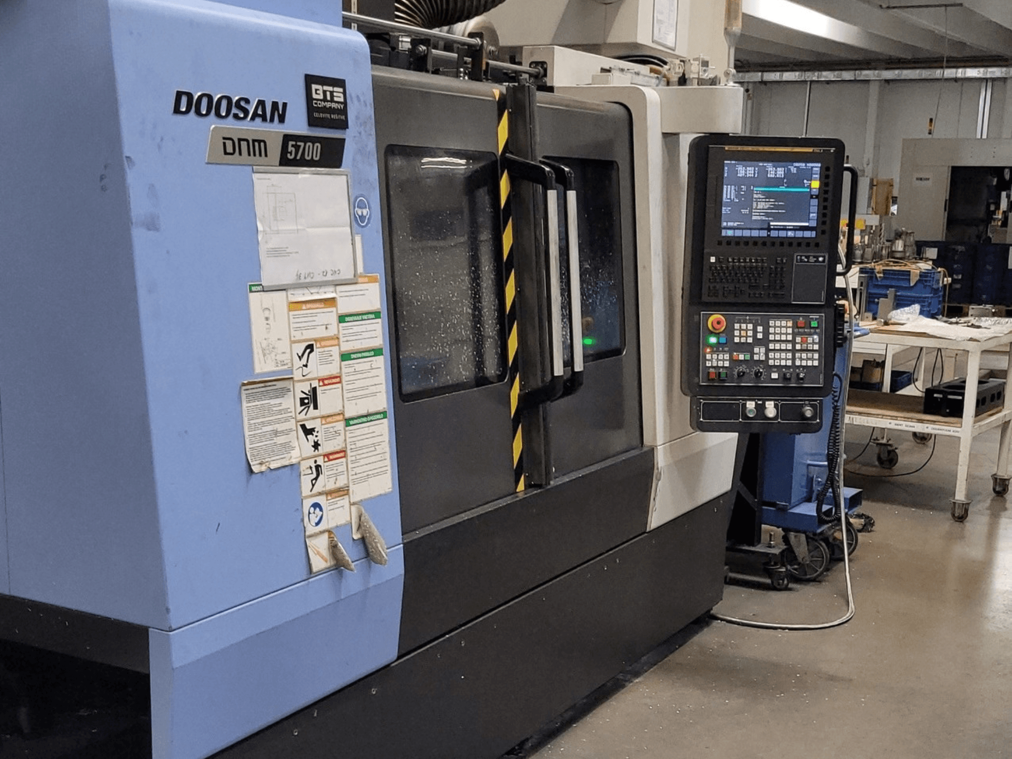 Vertikální obráběcí centrum DOOSAN DNM 5700, pohled zepředu, na kterém je vidět ovládací panel a ovládací prvky.