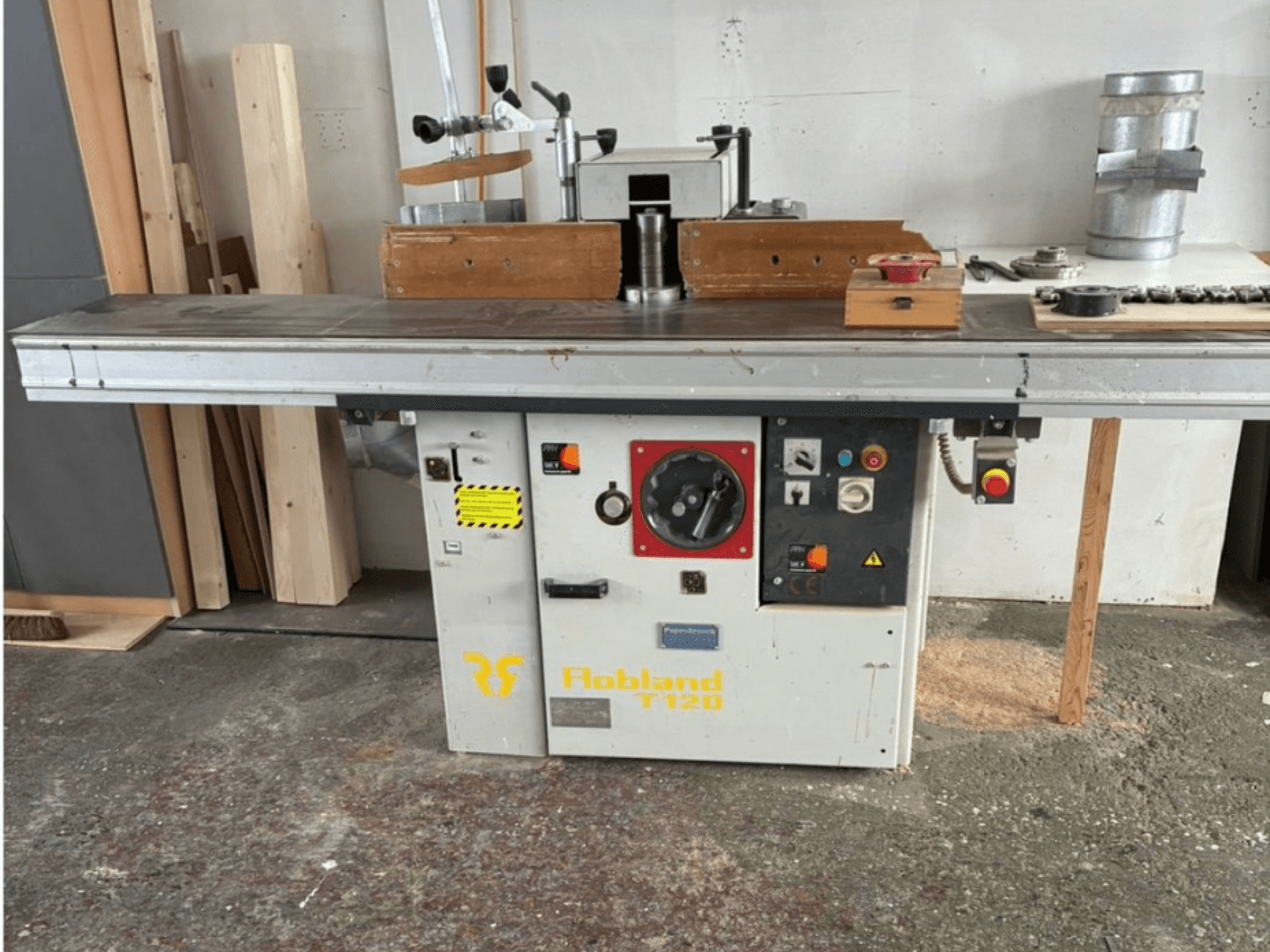 Stolní hoblík Hobbland T120, pohled zepředu, má stříbrný povrch, ovládací panel s tlačítky a bezpečnostní štítky.